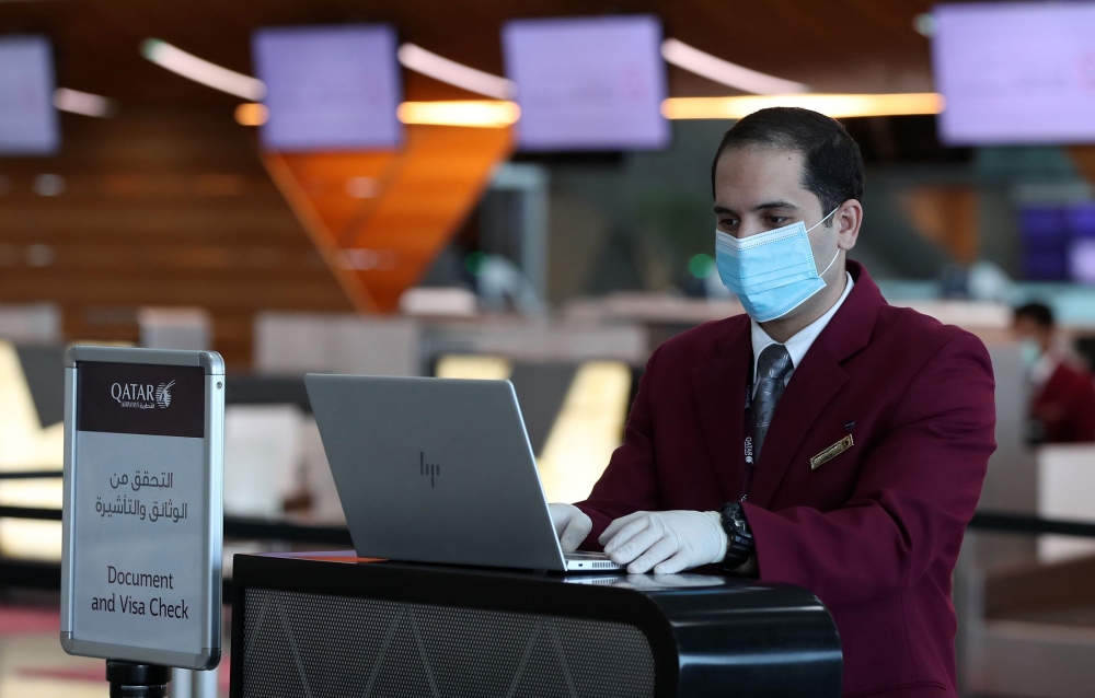 A check-in counter staff wears a mask and gloves at Doha's Hamad International Airport amid measures implemented to prevent the COVID-19 spread on March 31, 2020. AFP / Karim Jaafar 