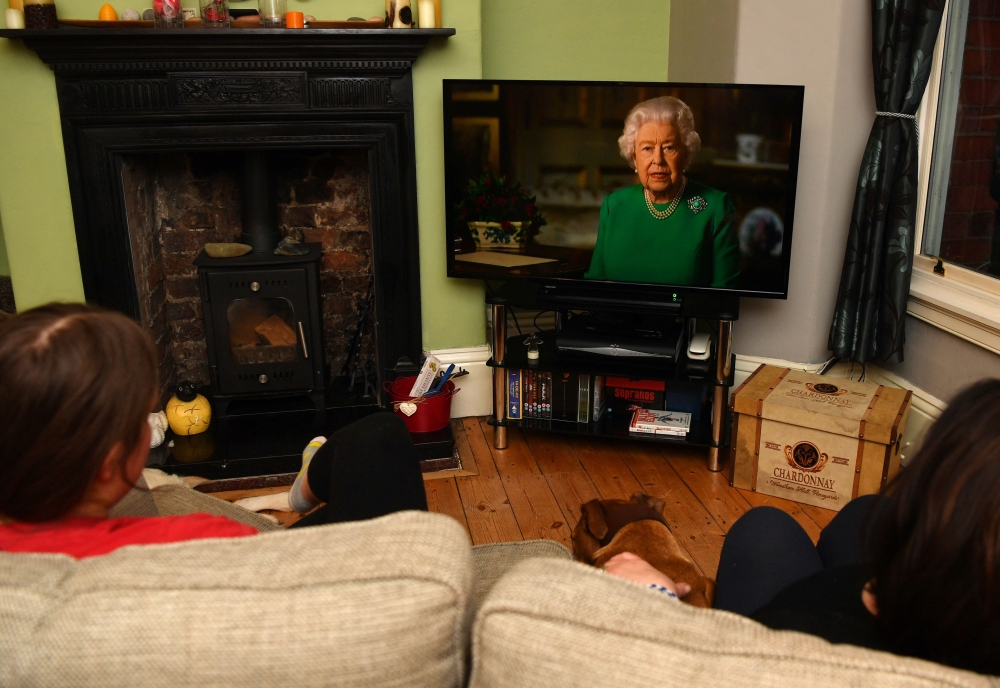 A picture shows a family in Birkenhead, northwest England on April 5, 2020 watching Britain's Queen Elizabeth II deliver a special address to the UK and Commonwealth recorded at Windsor Castle in relation to the coronavirus outbreak. AFP / PAUL ELLIS