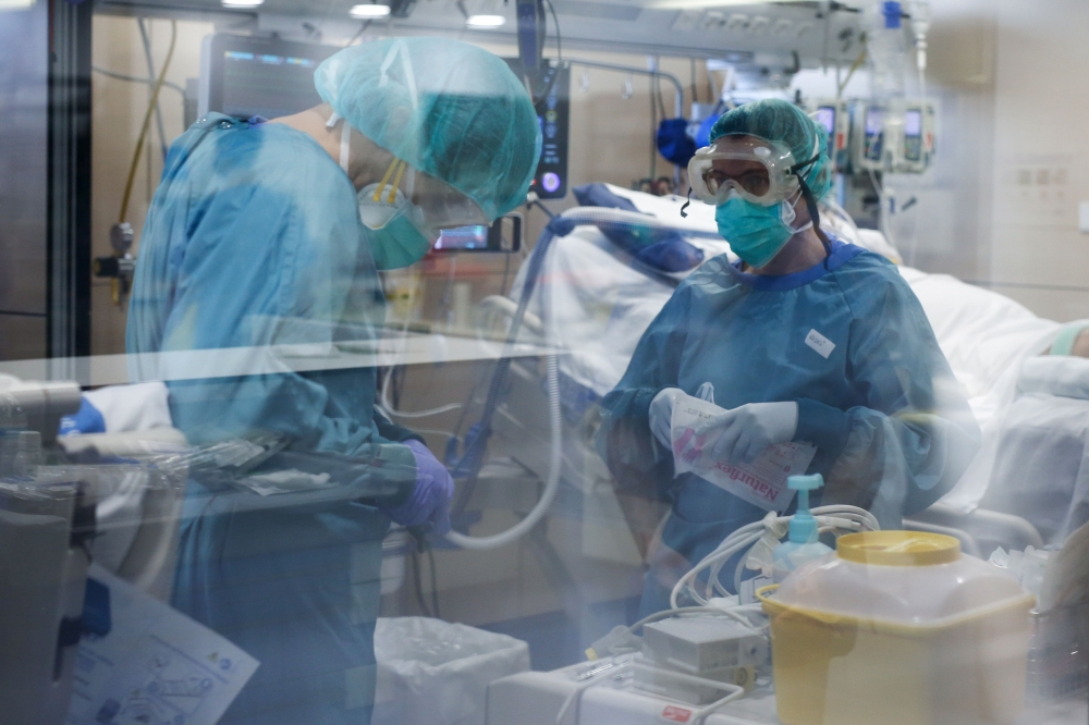 Healthcare workers wearing protective suits get ready to attend to a COVID-19 coronavirus patient at the Intensive Unit Care (ICU) of the Vall d'Hebron Hospital in Barcelona on April 6, 2020. Spain declared a fourth consecutive drop in the number of coron
