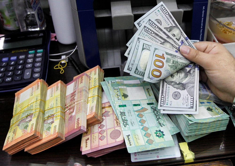 A man counts U.S. dollar banknotes next to Lebanese pounds at a currency exchange shop in Beirut, Lebanon April 24, 2020. REUTERS/Mohamed Azakir