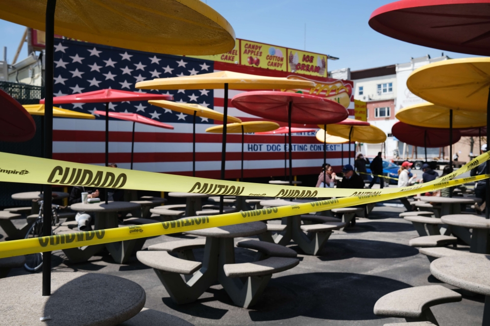 NEW YORK, NY - APRIL 25: Despite caution tape blocking off a seating section due to the coronavirus, people still sit down to enjoy a spring afternoon at Brooklyn's Coney Island on April 25, 2020 in New York City. Spencer Platt/AFP 