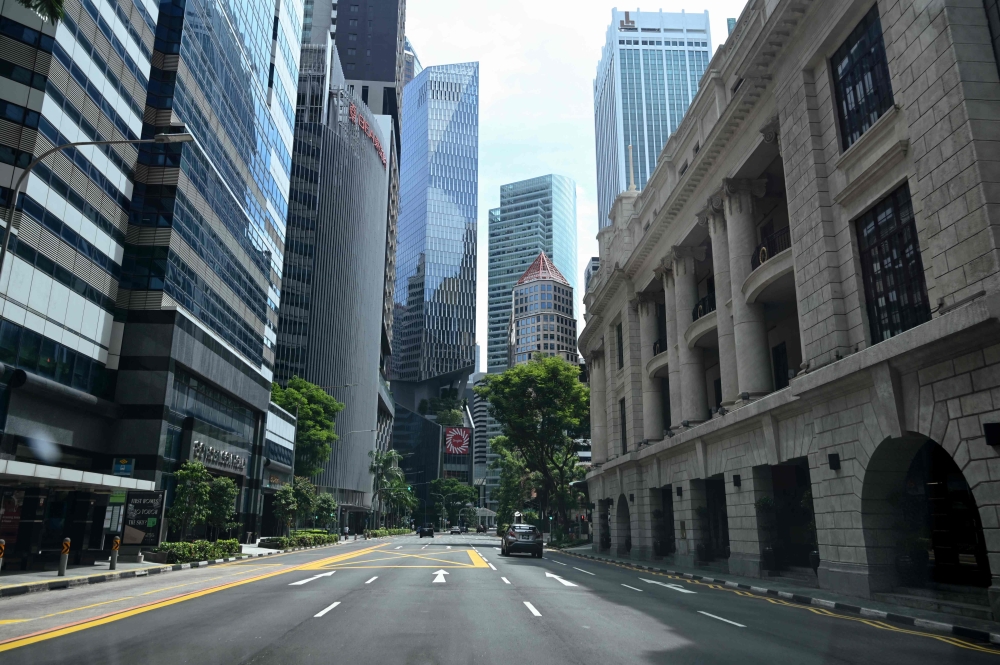 A car drives along an otherwise empty road in the financial district of Singapore on April 24, 2020, as the country undergoes a partial lockdown to fight the spread of the COVID-19 novel coronavirus. / AFP / Roslan RAHMAN
