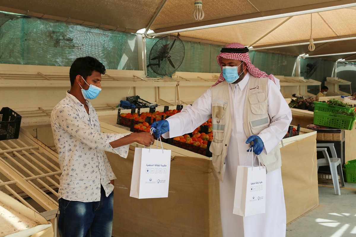 A Qatar Charity official giving health bag to worker in line with QC's continued efforts to fight the spread of COVID-19.