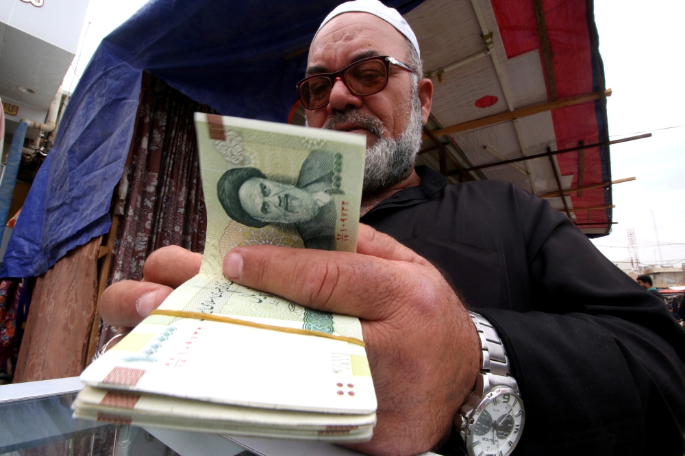 FILE PHOTO: A man buys Iranian rials from a seller of Iranian currency, before the start of the U.S. sanctions on Tehran, in Basra, Iraq November 3, 2018. Picture taken November 3, 2018. REUTERS/Essam al-Sudani