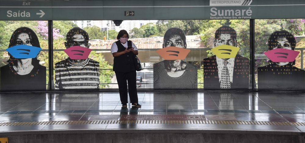 A woman awaits for the subway standing next to the Brazilian artist Alex Flemming work 