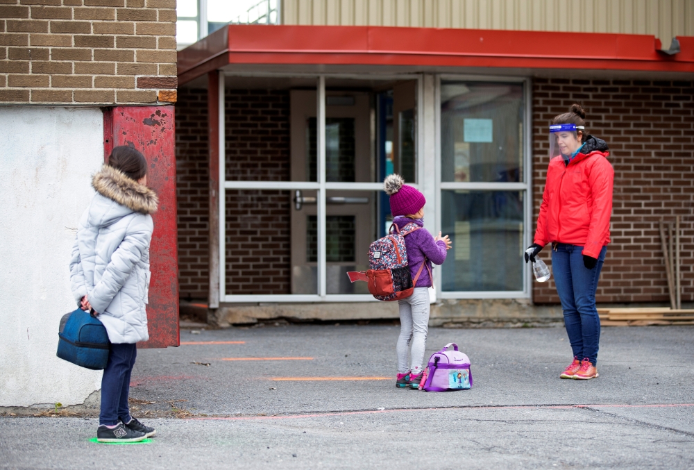 Students line up to have their hands sanitized in the schoolyard, as schools outside the greater Montreal region begin to reopen their doors amid the coronavirus disease (COVID-19) outbreak, in Saint-Jean-sur-Richelieu, Quebec, Canada May 11, 2020. REUTER
