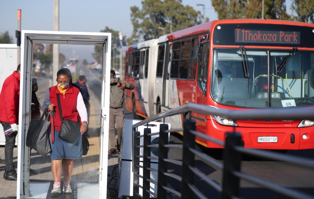 A commuter reacts as she is sprayed with sanitiser via walk-through 'tunnels' before boarding public transport, as South African President Cyril Ramaphosa said on Wednesday he aims to further ease restrictions imposed to curb the coronavirus disease (COVI