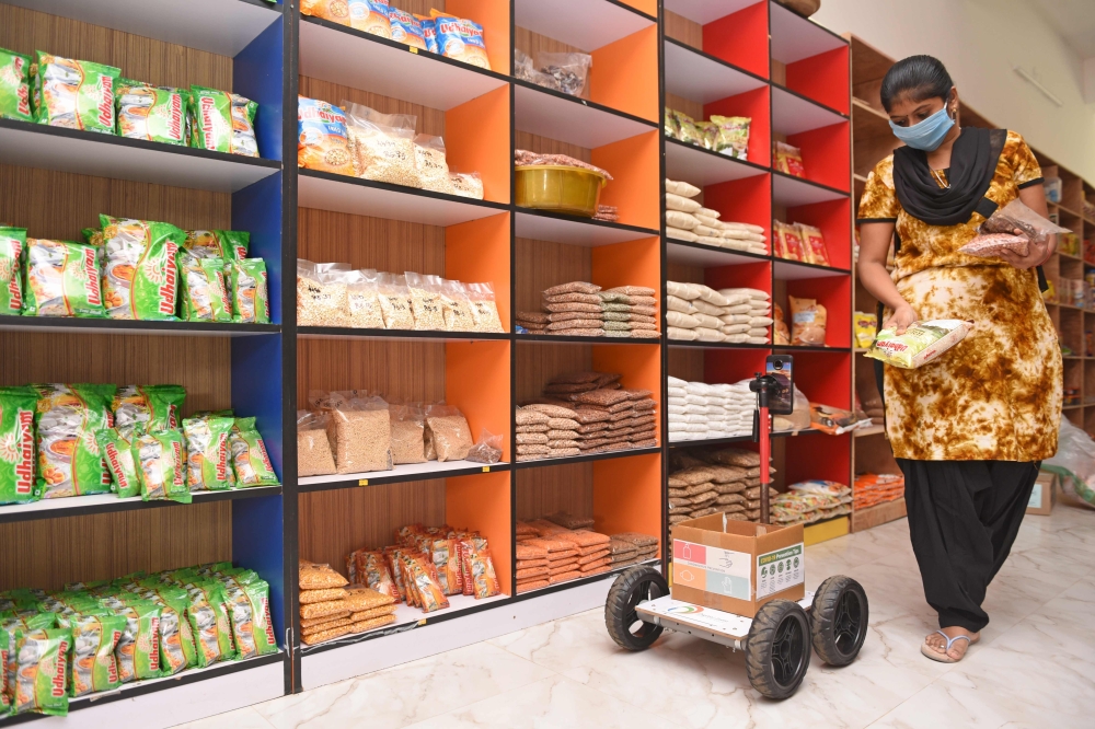 A store worker fills the tray of the robot with food items in Coimbatore, on May 13, 2020. AFP / STR