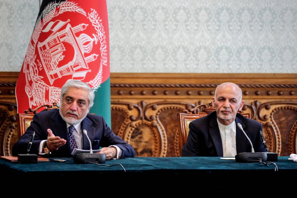 In this handout photograph taken on May 17, 2020 and released by Afghanistan's Office of Chief Executive, politician Abdullah Abdullah (L) gestures as he speaks next to Afghan President Ashraf Ghani (R) ahead of signing a power-sharing deal agreement at t