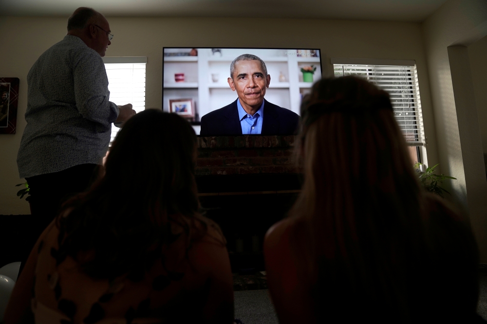 Torrey Pines High School graduating student Phoebe Seip, 18 (right), her father Jake, 57, and her sister Sydney, 22, watch former United States President Barack Obama deliver a virtual commencement address to millions of high school seniors who will miss 