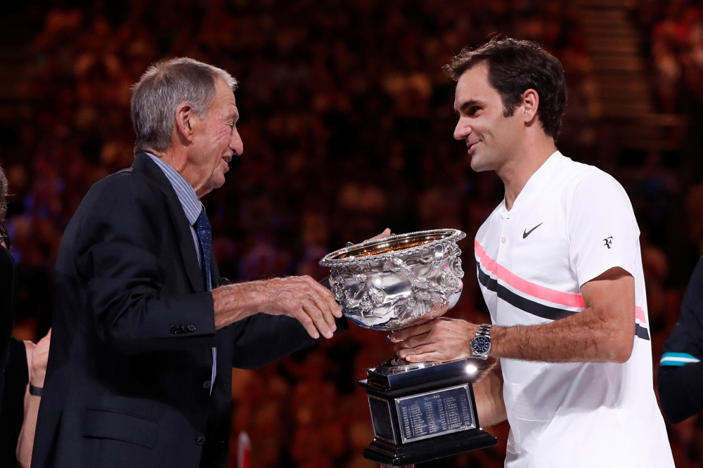 FILE PHOTO: Tennis - Australian Open - Men's singles final - Rod Laver Arena, Melbourne, Australia, January 28, 2018. Switzerland's Roger Federer is presented with the trophy by former player Ashley Cooper after winning the final against Croatia's Marin C