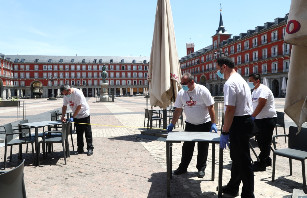 Workers use measuring tape to check social distancing as they set up a terrace which will be allowed to open from May 25, amid the coronavirus disease (COVID-19) outbreak, at Plaza Mayor Square in Madrid, Spain, May 24, 2020. REUTERS/Sergio Perez