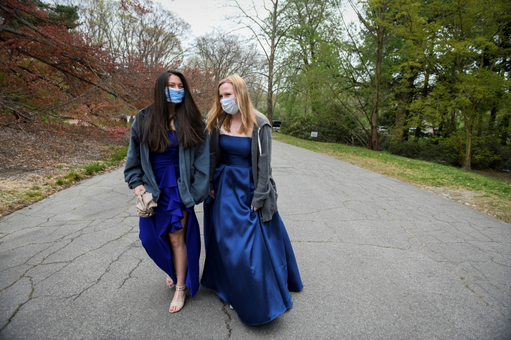 Caroline Afonso and MK Rusnock, high school seniors graduating from Ursuline Academy, walk through the Arnold Arboretum while posing for photographs for Reuters in their prom dresses, after prom was cancelled due to the coronavirus disease (COVID-19) outb