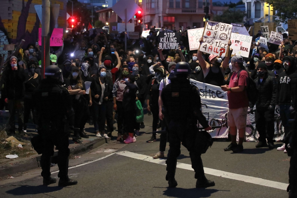 Demonstrators hold signs in front of California Highway Patrol officers during a protest sparked by the death of George Floyd while in police custody on May 29, 2020 in Oakland, California. Justin Sullivan/Getty Images/AFP