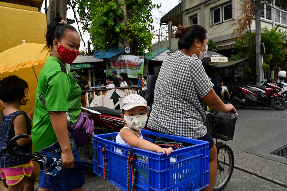 This photo taken on May 25, 2020 shows a child sitting in a plastic box as her mother cycles after receiving food donations for families affected by the COVID-19 novel coronavirus outbreak at the Holy Redeemer Catholic church in Bangkok. AFP / Romeo Gacad