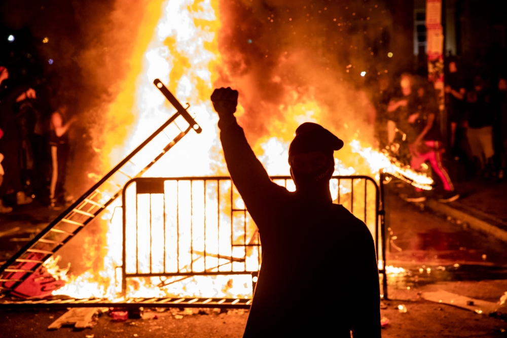 TOPSHOT - A protester raises a fist near a fire during a demonstration outside the White House over the death of George Floyd at the hands of Minneapolis Police in Washington, DC, on May 31, 2020.  / AFP / Samuel Corum

