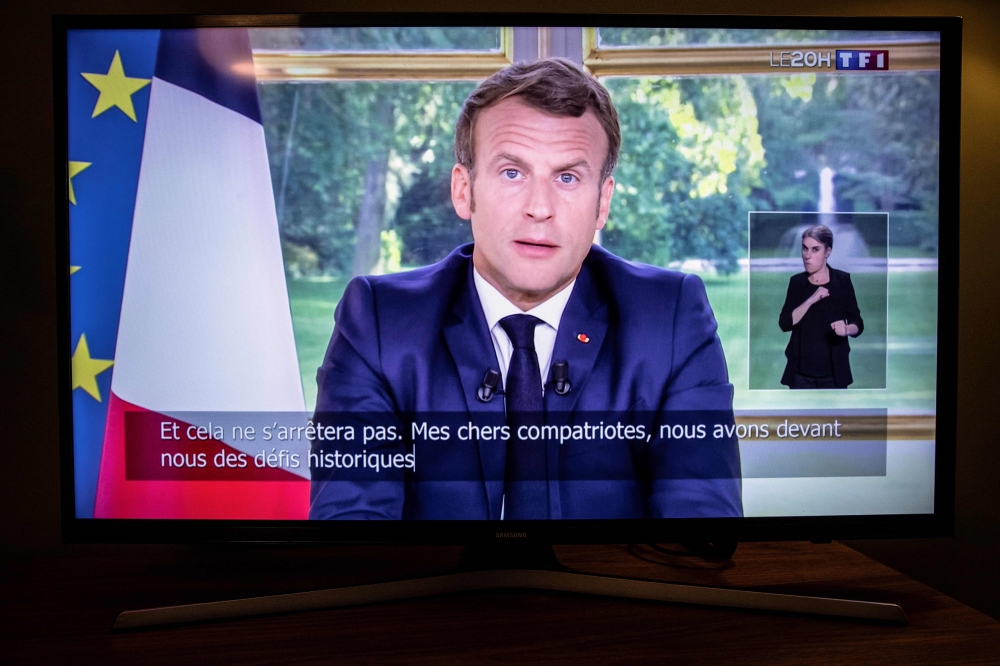 French President Emmanuel Macron is seen on a television screen in Paris on June 14, 2020 as he addresses the nation from the Elysee Palace during a televised speech, broadcast by French tv channel TF1. / AFP / Thomas Samson 