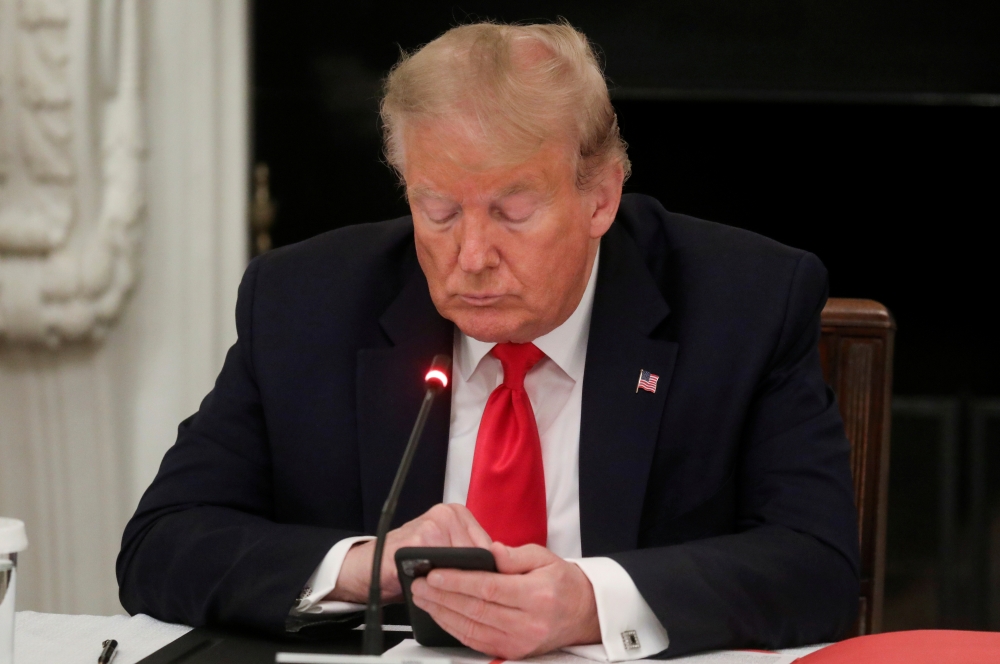 U.S. President Donald Trump uses a mobile phone during a roundtable discussion on the reopening of small businesses in the State Dining Room at the White House in Washington, U.S., June 18, 2020. REUTERS/Leah Millis 