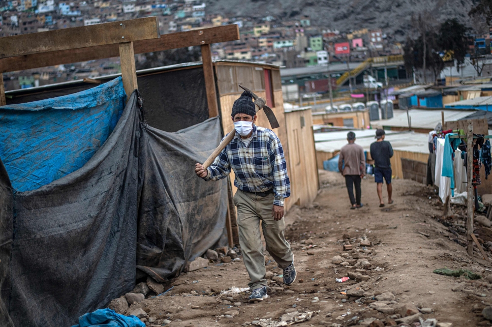 A man carrying a pick walks at the Cantagallo community, where some 300 families of the Shipibo Conibo ethnic group inhabit, in Lima on June 18, 2020. AFP / ERNESTO BENAVIDES
