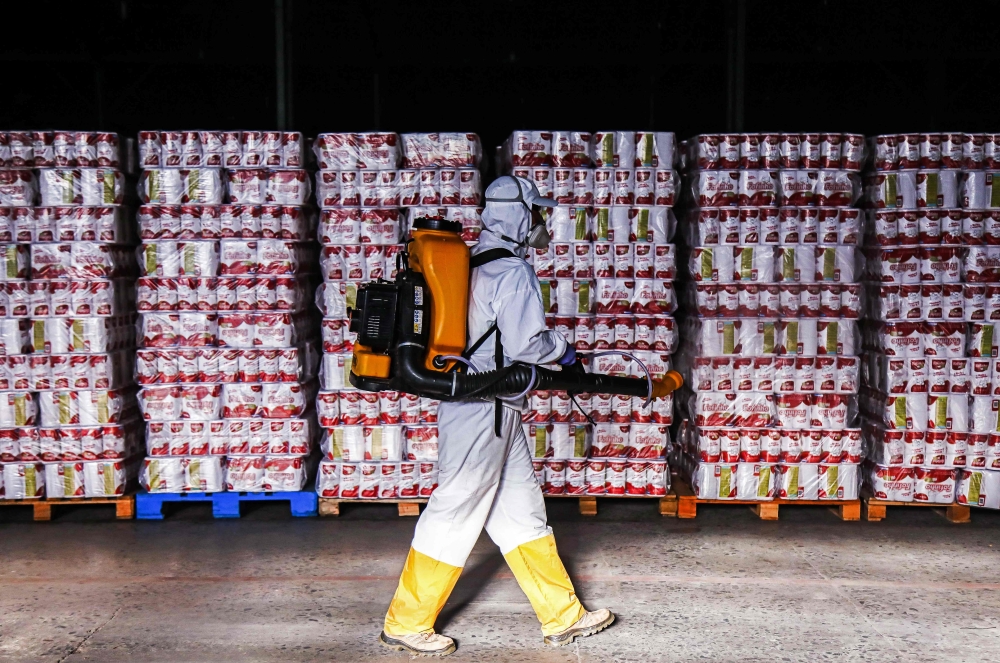 An employee disinfects supplies at a municipal warehouse in Curitiba, Brazil, on June 19, 2020. / AFP / DANIEL CASTELLANO