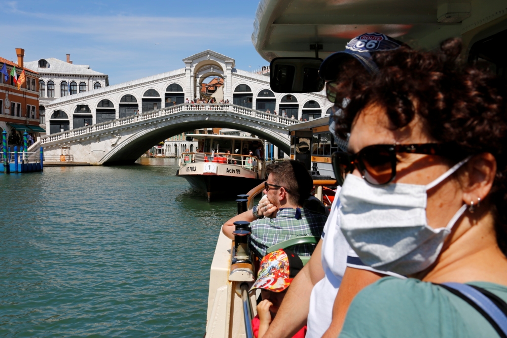 Tourists wear face masks as they pass the Rialto Bridge on a vaporetto (water taxi), amid the coronavirus disease (COVID-19) outbreak, in Venice, Italy June 21, 2020. REUTERS/Fabrizio Bensch