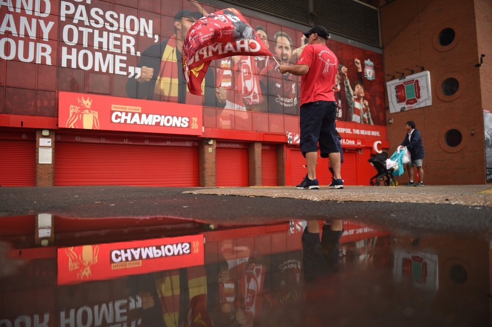 A fan waves a flag outside Anfield stadium in Liverpool, north-west England on June 26, 2020 after Liverpool sealed the Premier League title the previous evening.   AFP / Oli SCARFF
