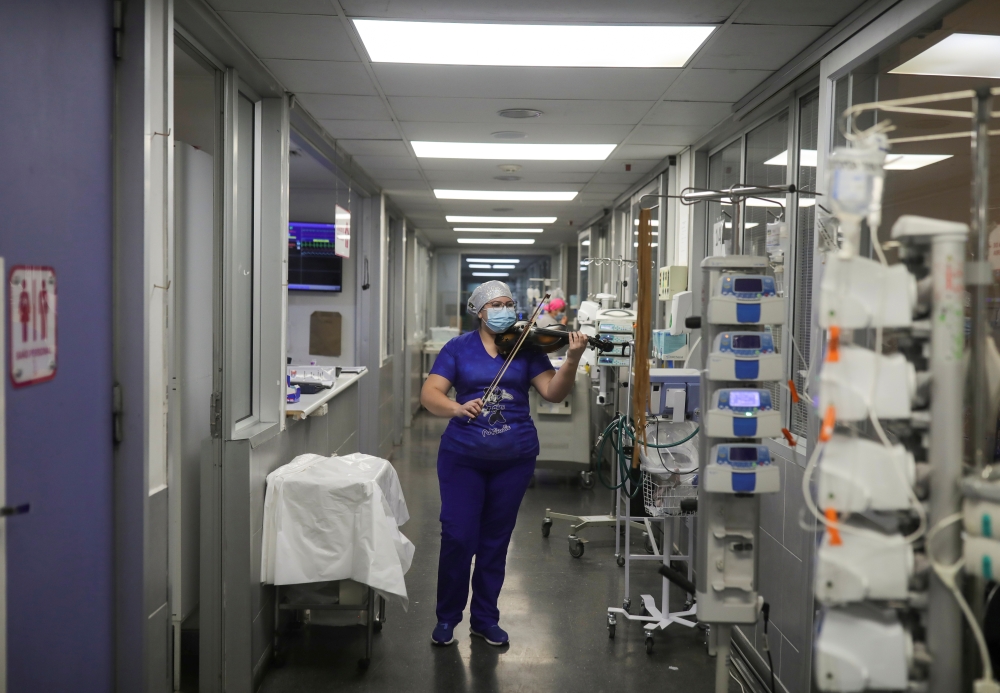 Chilean nurse Damaris Silva plays the violin for patients suffering from the coronavirus disease (COVID-19) in the Intensive Care Unit (ICU) of the El Pino de San Bernardo hospital, in Santiago, Chile, July 2, 2020. REUTERS/Pablo Sanhueza
