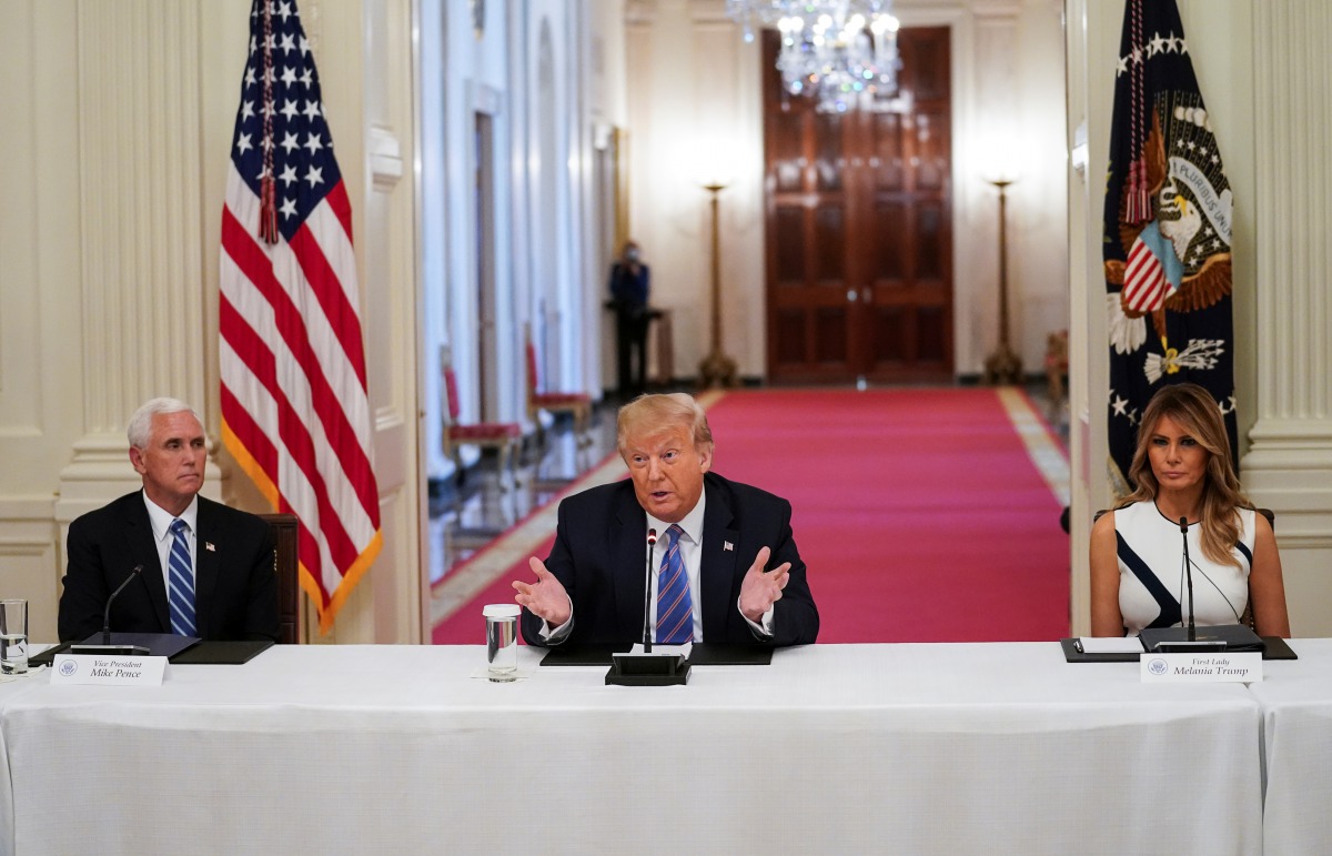 U.S. President Donald Trump is flanked by Vice President Mike Pence and first lady Melania Trump as he speaks during an event on reopening schools amid the coronavirus disease (COVID-19) pandemic in the East Room at the White House in Washington, U.S., Ju