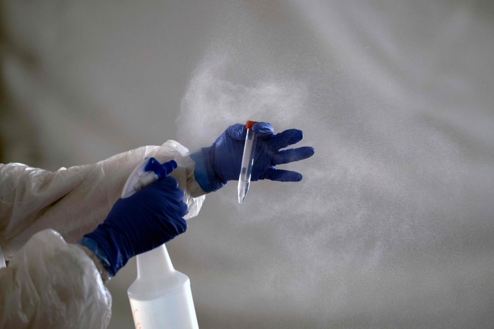 A laboratory worker cleans the tube containing a sample from a customer at the Certus Lab's COVID-19 drive-thru test centre at the parking lot of the Caliente multipurpose complex in Tijuana, Baja California State, Mexico, on July 21, 2020 amid the novel 