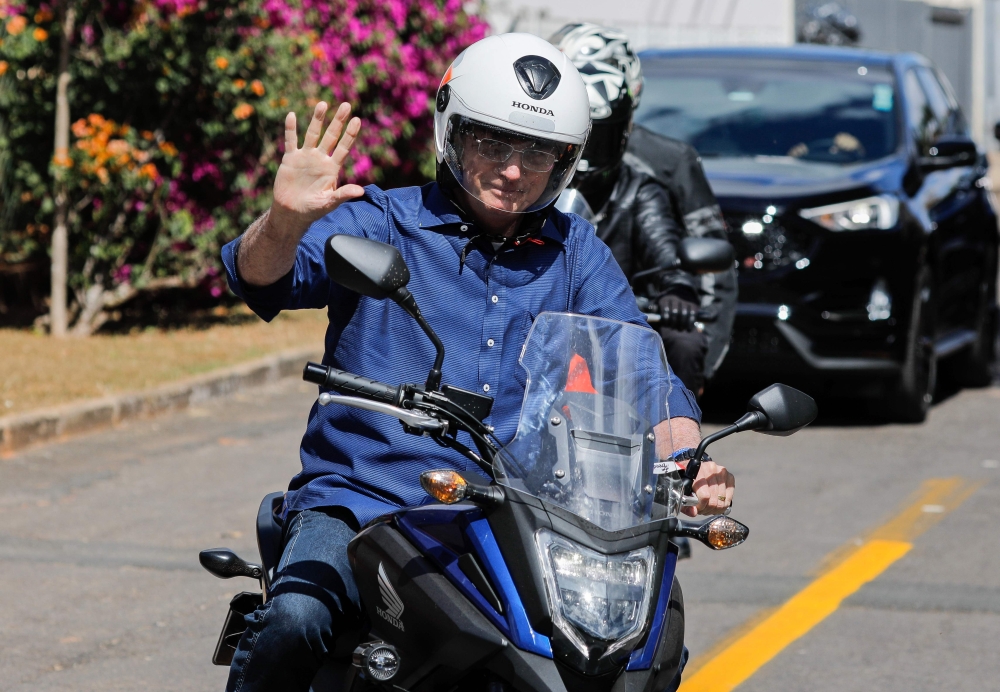 Brazilian President Jair Bolsonaro waves as he takes a ride after he announced he tested negative for COVID-19 more than two weeks after being diagnosed, in Brasilia, on July 25, 2020. (AFP / Sergio LIMA)