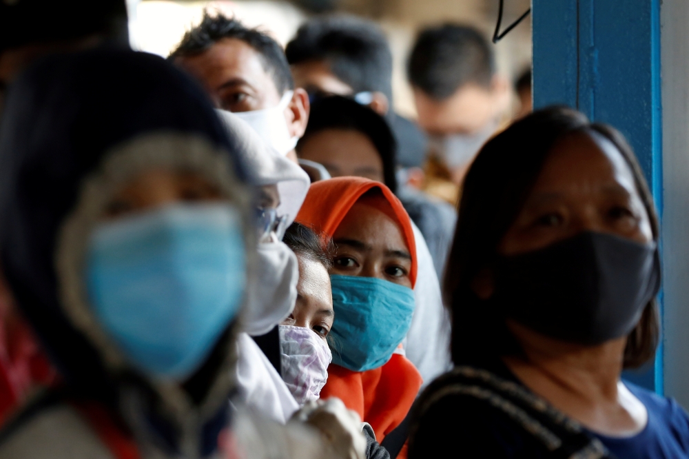 Passengers wearing protective face masks queue for a public bus, following the coronavirus disease (COVID-19) outbreak, at a central bus spot in Jakarta, Indonesia, July 27, 2020. REUTERS/Willy Kurniawan