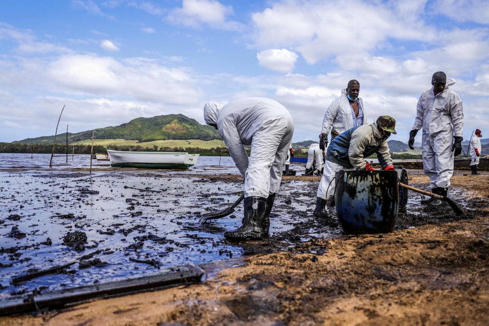 People scoop leaked oil from the vessel MV Wakashio, belonging to a Japanese company but Panamanian-flagged, that ran aground and caused oil leakage near Blue bay Marine Park in southeast Mauritius on August 9, 2020.  AFP / L'Express Maurice / Daren Maure