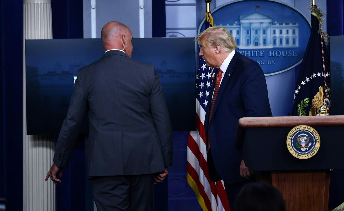 TOPSHOT - US President Donald Trump is being removed by a member of the secret service from the Brady Briefing Room of the White House in Washington, DC, on August 10, 2020. Secret Service guards shot a person, who was apparently armed, outside the White 