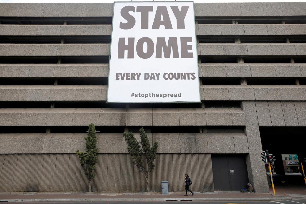 FILE PHOTO: A man walks beneath a billboard during the 21-day nationwide lockdown aimed at limiting the spread of coronavirus disease (COVID-19) in central Cape Town, South Africa, April 6, 2020. REUTERS/Mike Hutchings
