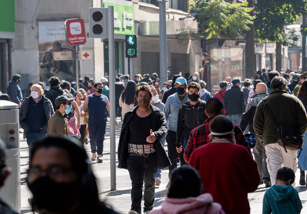 People wear face masks while walking along a pedestrian promenade in downtown Santiago, following the easing of lockdown restrictions amid the Covid-19 pandemic, on August 17, 2020. / AFP / Martin BERNETTI