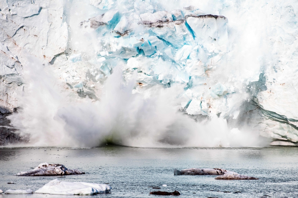 This file photo taken on August 17, 2019 shows an iceberg calving with a mass of ice breaking away from the Apusiajik glacier, near Kulusuk (aslo spelled Qulusuk), a settlement in the Sermersooq municipality located on the island of the same name on the s