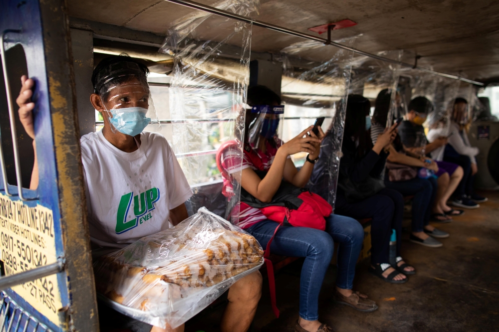 Jeepney passengers seated between plastic barriers, wear face masks and face shields mandatory in public transportation, to help curb coronavirus disease (COVID-19) infections, in Quezon City, Metro Manila, Philippines, August 19, 2020. REUTERS/Eloisa Lop
