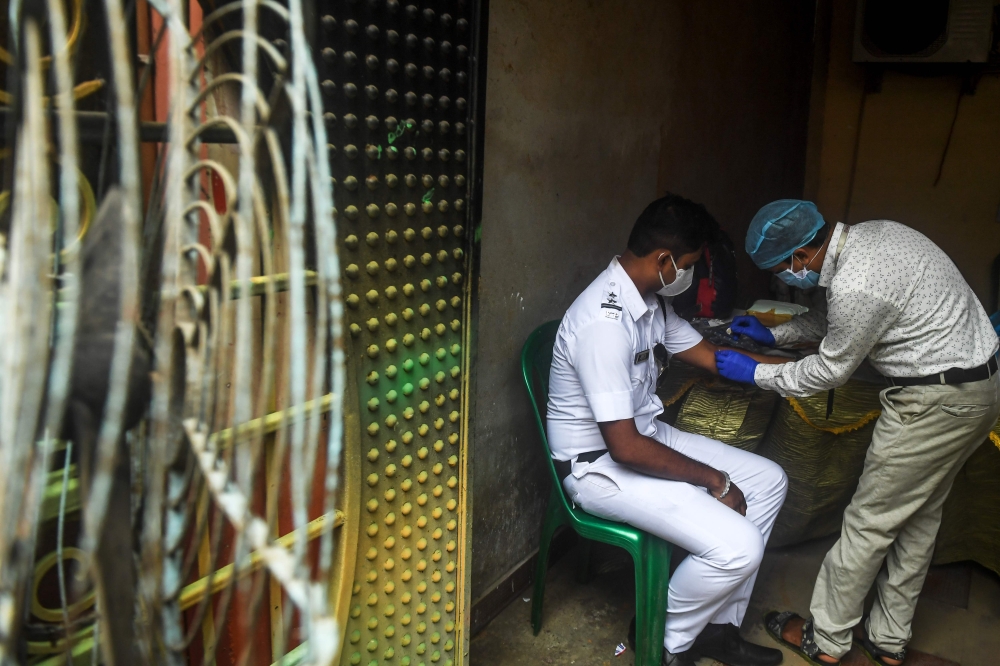 A health worker (R) collects a blood sample from a police official for antibodies test of COVID-19 coronavirus, in Kolkata on August 23, 2020. / AFP / Dibyangshu SARKAR