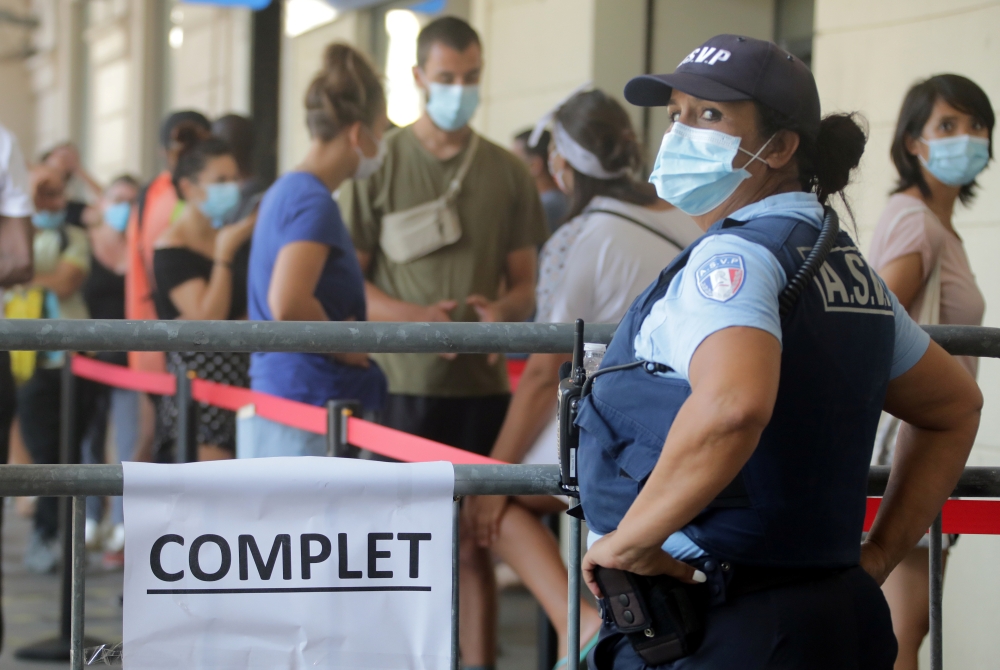 A French municipal police employee stands near a fence with a sign reading 
