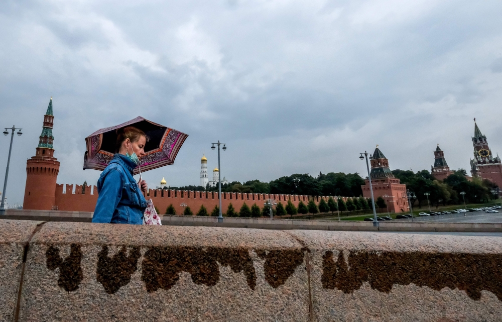 A woman wearing a face mask to protect against the coronavirus disease walks along a bridge near the Kremlin in Moscow on August 26, 2020. / AFP / Yuri KADOBNOV