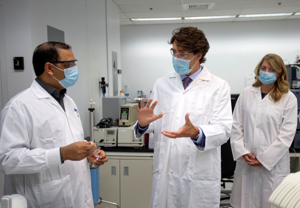 Canada's Prime Minister Justin Trudeau accompanied by Melanie Joly (R) Canada's Minister of Economic Development and Official Languages speaks with Krishnaraj Tiwari about vaccines at the National Research Council of Canada in Montreal, Quebec, Canada Aug