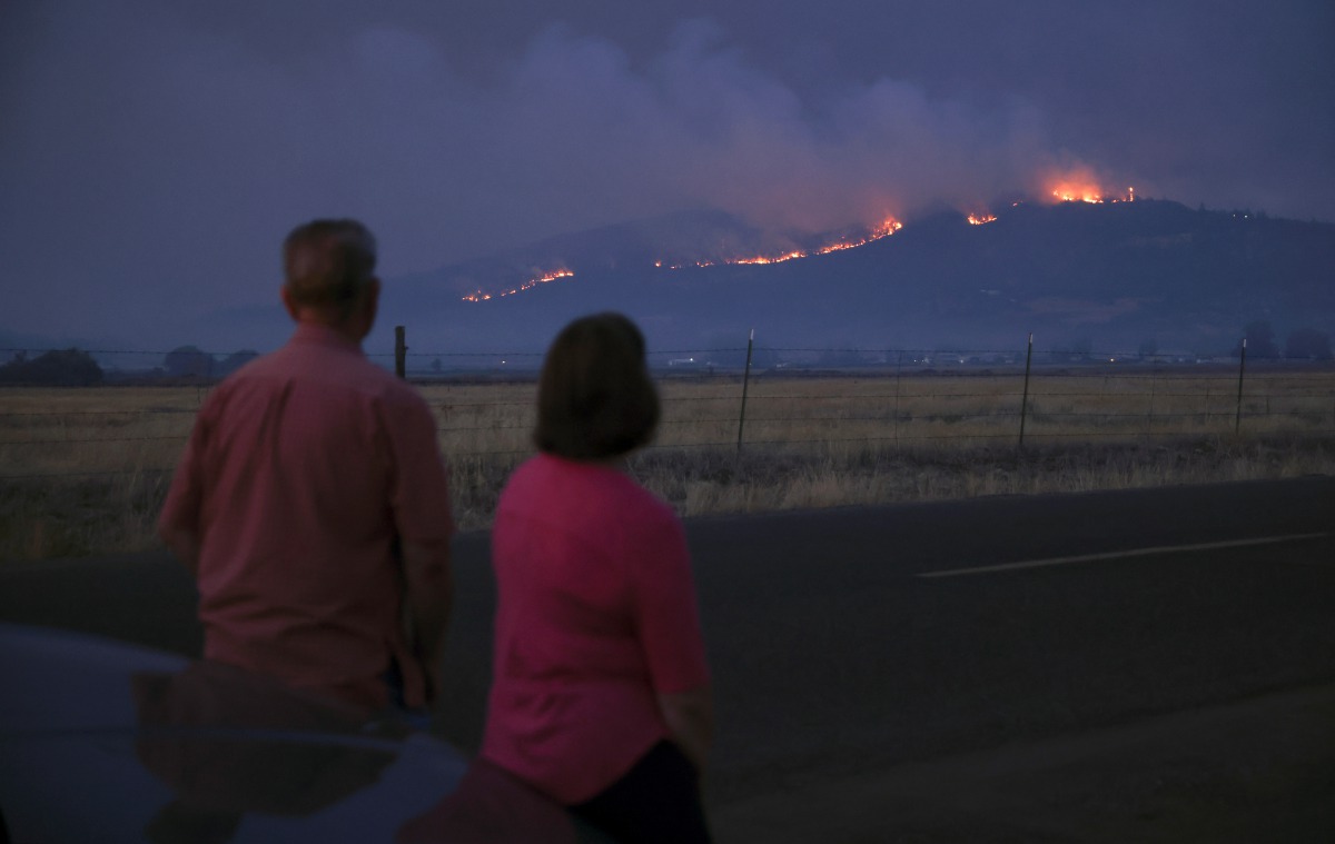 Local residents look at smoke and fire over a hill during wildfires near the town of Medford, Oregon, U.S. September 9, 2020. REUTERS/Carlos Barria
