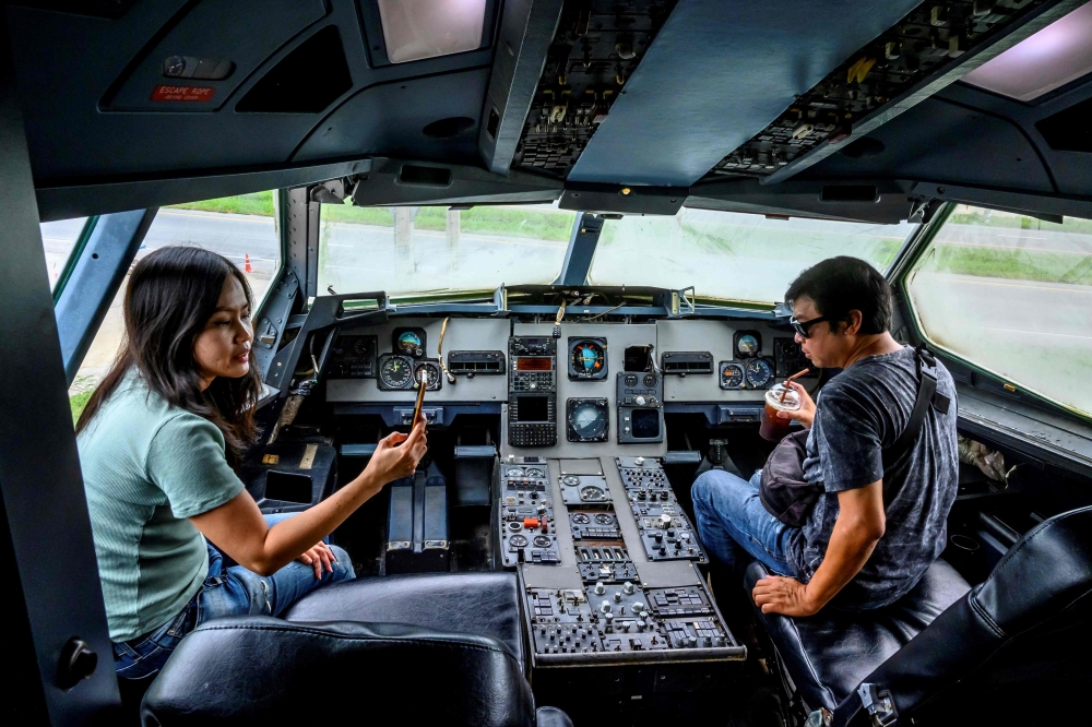 This photograph taken on September 1, 2020 shows visitors sitting in the cockpit of a retired Airbus 330 air-plane turned into a coffee shop at an attraction site, outside Pattaya in Chonburi province. With millions around the world stuck at home due to t