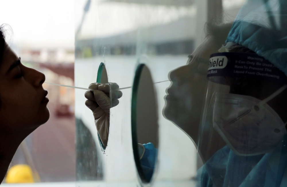 A health worker in personal protective equipment (PPE) collects a swab sample from a woman amidst the spread of the coronavirus disease (COVID-19) at Indira Gandhi International Airport, in New Delhi, India, September 12, 2020. REUTERS/Anushree Fadnavis