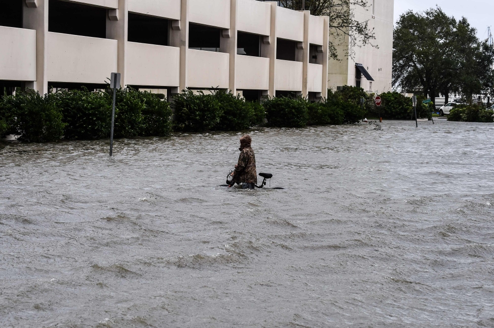 A man walks his bicycle through a street flooded by Hurricane Sally in Pensacola, Florida, on September 16, 2020. Hurricane Sally barrelled into the US Gulf Coast early Wednesday, with forecasts of drenching rains that could provoke 