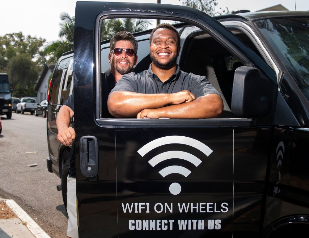 Roman Reyna (L) owner of JFK transportation and Kevin Watson (R), president of JFK transportation, pose with one of their company vans equipped as a mobile Wifi Hotspot to help students access internet to remotely attend their classes, September 16, 2020,