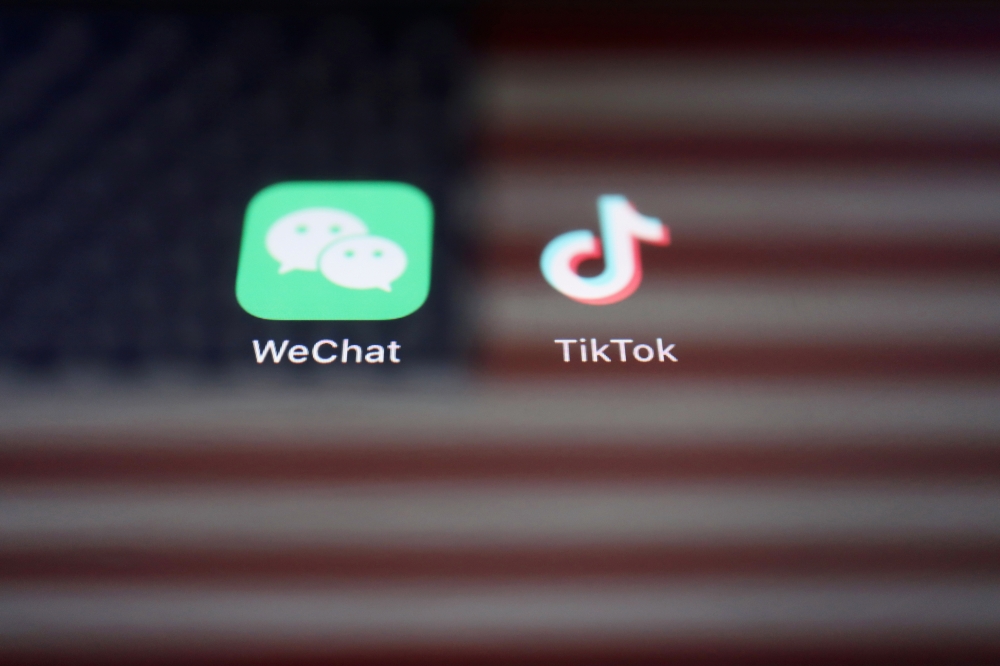 A reflection of the US flag is seen on the signs of the WeChat and TikTok apps in this illustration picture taken on September 19, 2020. REUTERS/Florence Lo/Illustration