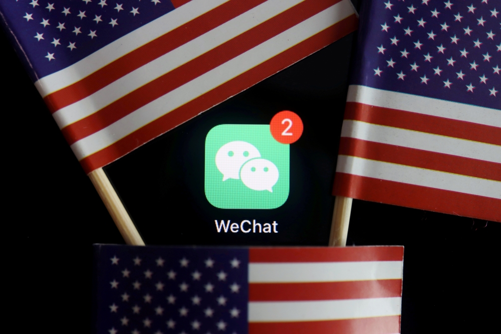 FILE PHOTO: The messenger app WeChat is seen among U.S. flags in this illustration picture taken Aug. 7, 2020. Reuters/Florence Lo/Illustration/File Photo