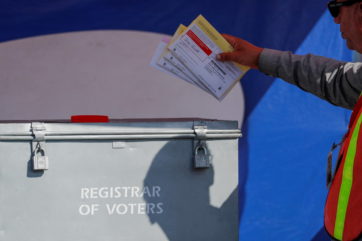 FILE PHOTO: An election worker places mail-in ballots into an election box at a drive-through drop off location at the Registrar of Voters in San Diego, California, U.S. November 5, 2018. REUTERS/Mike Blake/File Photo
