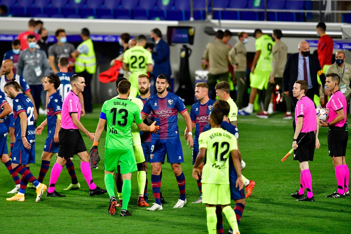 Players shake hands at the end of the Spanish league football match SD Huesca against Club Atletico de Madrid at the El Alcoraz stadium in Huesca on September 30, 2020. / AFP / Pau BARRENA
